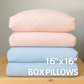 Stack of four box bamboo Claire De Lune Cloud pillows in pink and blue on a wooden surface with a neutral background.