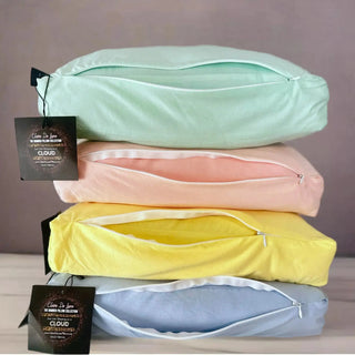 Stack of four 16x16x3 inch bamboo cloud pillows in pastel mint, light pink, yellow, and light blue, each with a soft zippered cover and a discreet, hidden zipper design.