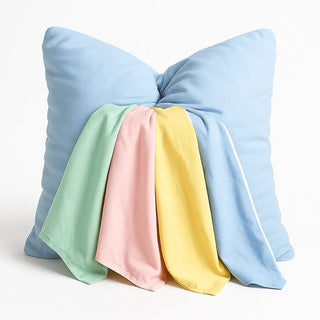 Pastel-colored cloud case pillow covers draped over a blue Claire De Lune Cloud Co. pillow on a white background