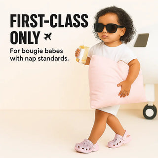Child in a pink and white dress with sunglasses holding a cup and a Bamboo Cloud Technology pillow by Claire De Lune Cloud Co. with text about 'first-class only' and 'bougie babes with nap standards'.